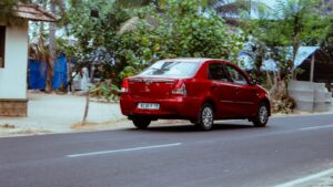 a small red car driving down a street