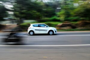 a white car driving down a street next to a forest