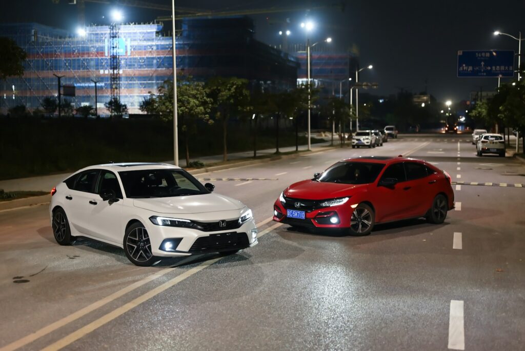 Two cars are parked on a road at night.