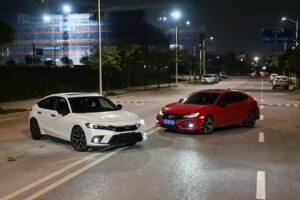 Two cars are parked on a road at night.